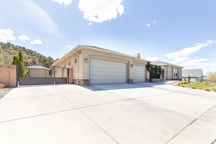 View of front of home with a gate, concrete driveway, a garage, stone siding, and stucco siding
