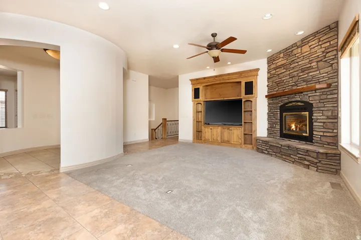 Unfurnished living room with light carpet, light tile patterned floors, a ceiling fan, arched walkways, and recessed lighting