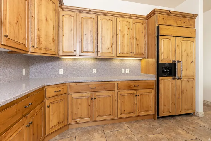 Kitchen featuring backsplash, paneled built in refrigerator, light stone counters, and wood finish cabinets