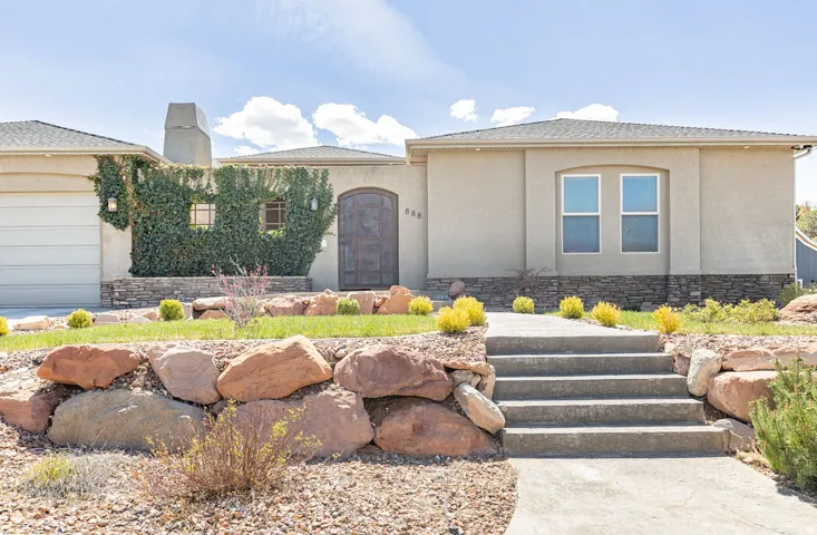 View of front of home featuring stucco siding, an attached garage, a chimney, and stone siding