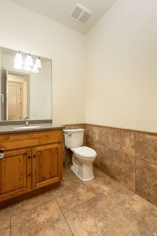 Bathroom with vanity, wainscoting, and tile walls