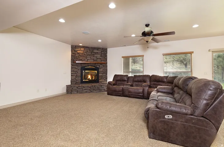 Carpeted living area with a ceiling fan, a fireplace, and recessed lighting
