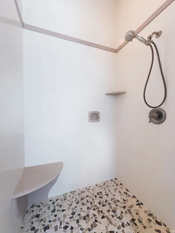 Bathroom featuring a tile shower and light stone finish floors