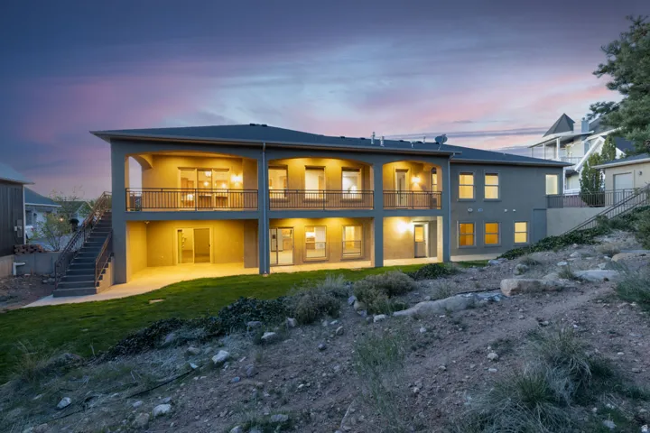 Back of property at dusk featuring stucco siding, a patio, and a balcony