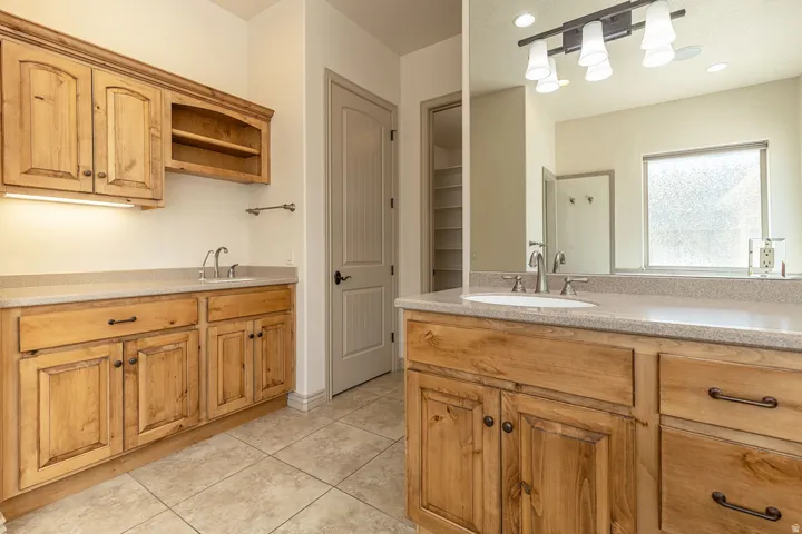 Full bathroom featuring two vanities and light tile patterned floors