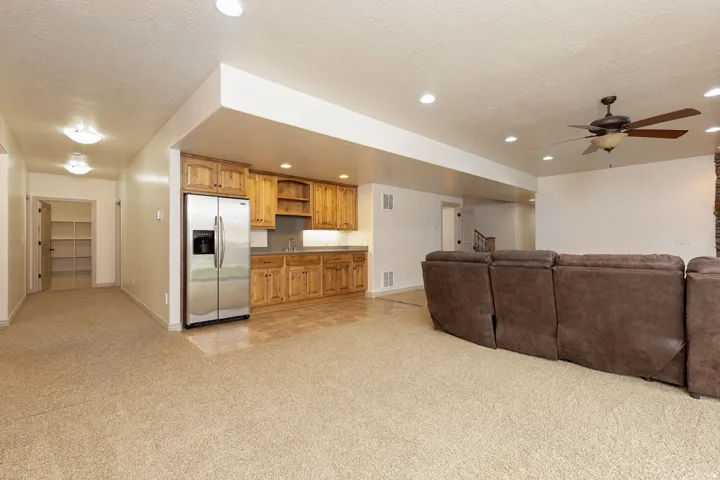 Living room featuring light carpet, a ceiling fan, a textured ceiling, and recessed lighting