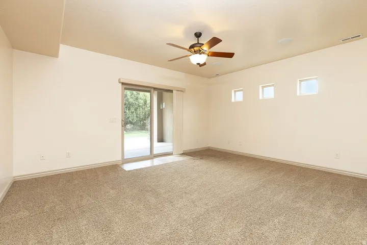 Unfurnished room with a ceiling fan and light colored carpet