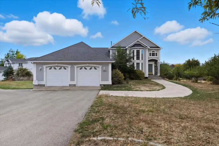 Traditional home with a shingled roof, a front lawn, driveway, and an attached garage