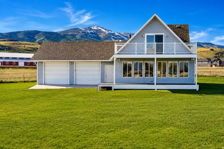 Gable-front home featuring light blue siding, a covered lower porch, and an upper-level balcony with white railings.