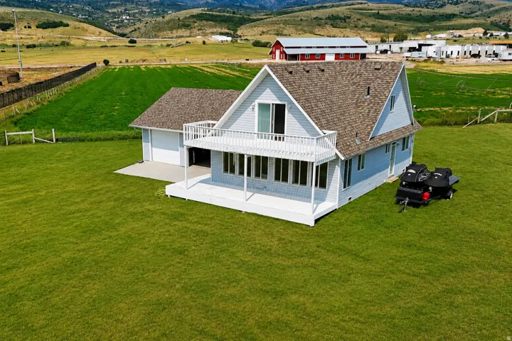 Light blue siding residence with a composition shingle roof, featuring a two-car garage, an upper-level balcony, and a covered porch