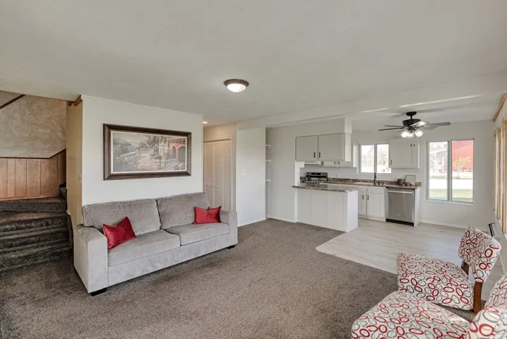 Living area with ceiling fan, light colored carpet, and wood walls