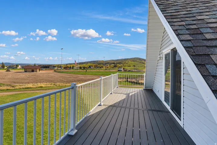 Spacious outdoor deck featuring composite decking and white railing, with a sliding glass door providing access to the interior
