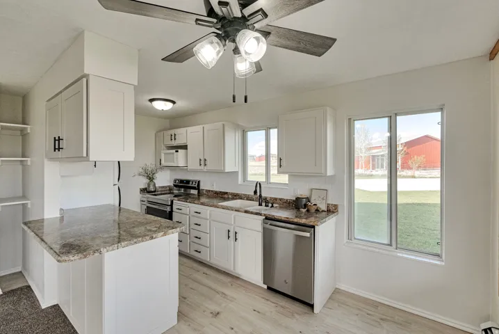 Kitchen with stainless steel appliances, light wood-style floors, white cabinets, and a peninsula