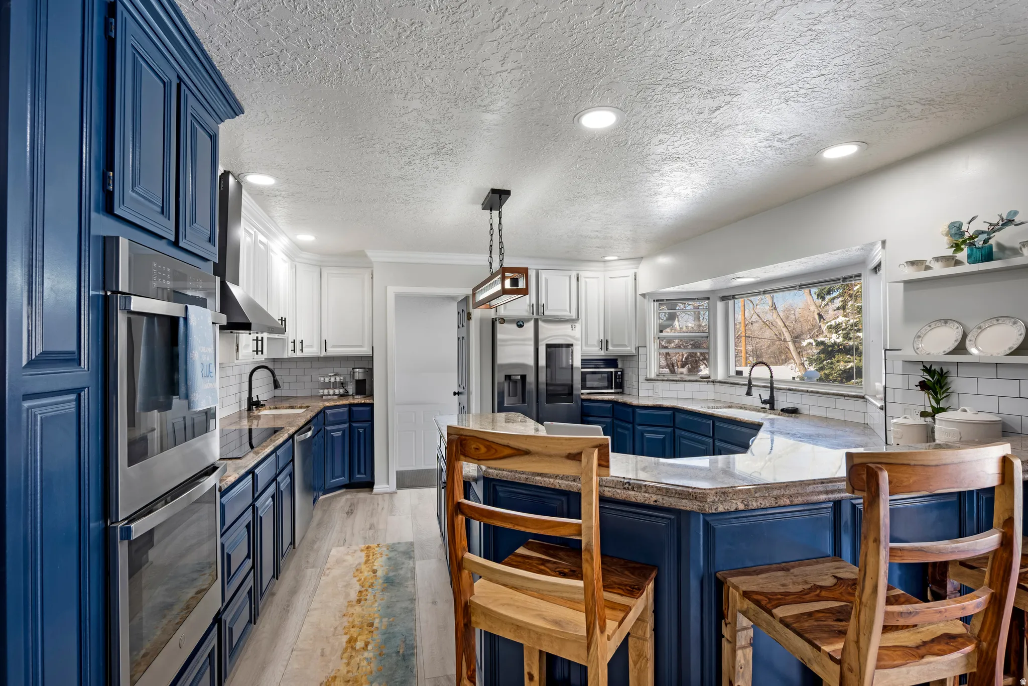 Dual tone kitchen with stainless steel appliances, a peninsula, a kitchen breakfast bar, dual tone cabinetry, and a textured ceiling