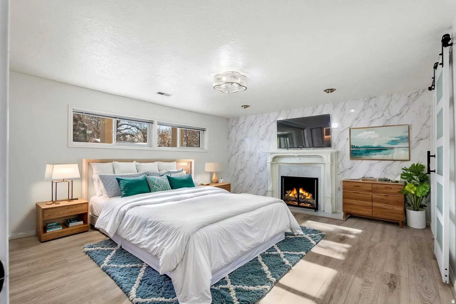 Bedroom featuring a barn door, light wood finished floors, and a premium fireplace