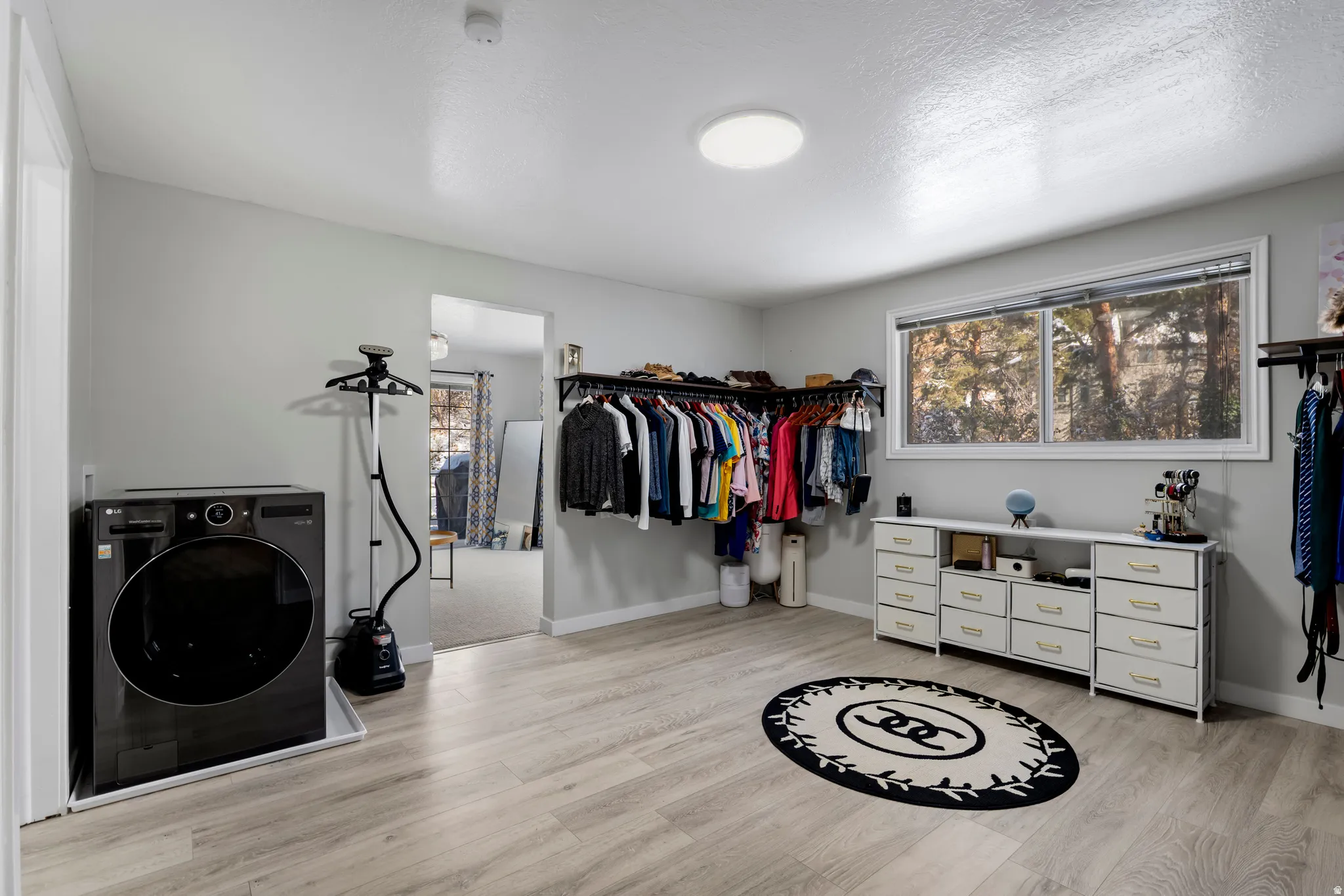 Laundry room with washer / clothes dryer, light wood-style flooring, and a textured ceiling