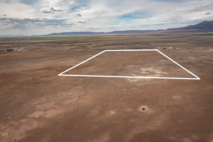 Aerial view of sparsely populated area with a mountainous background and property parcel outlined