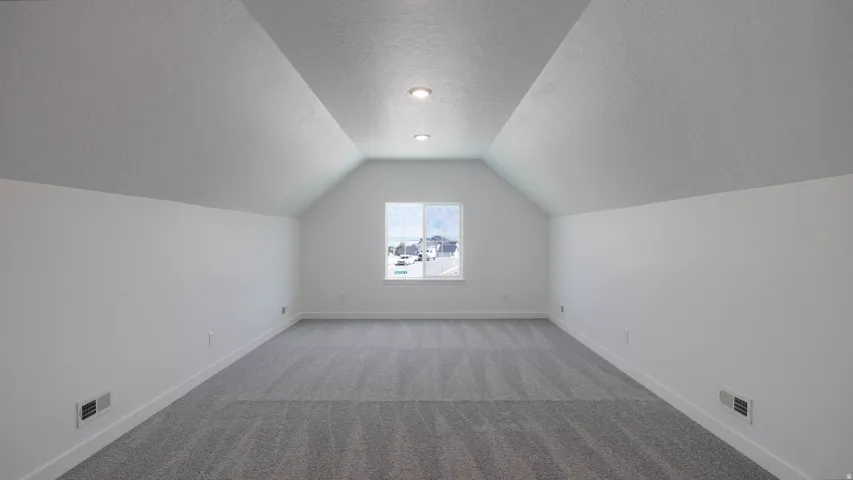 Additional living space featuring a textured ceiling and light colored carpet