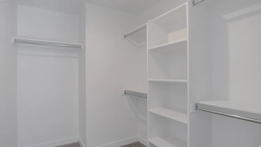 Walk in closet featuring dark carpet