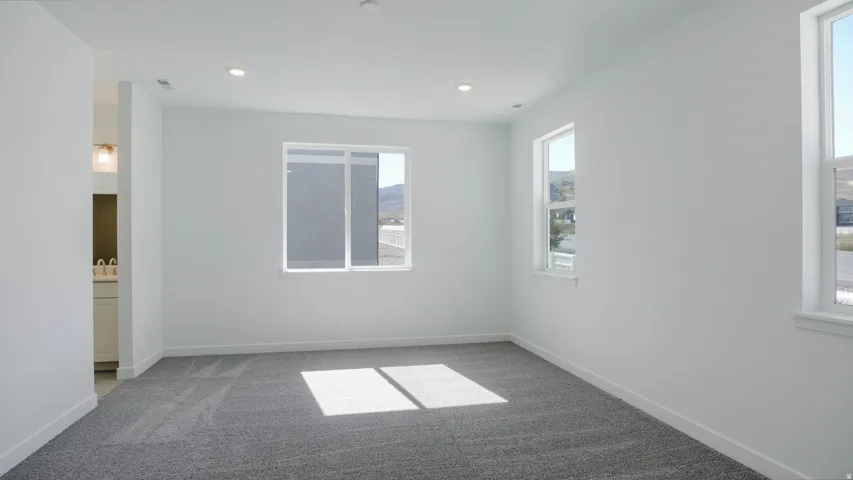 Empty room with light carpet and recessed lighting