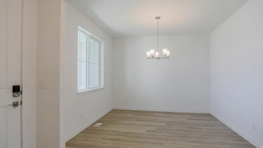 Unfurnished dining area with light wood finished floors and a chandelier
