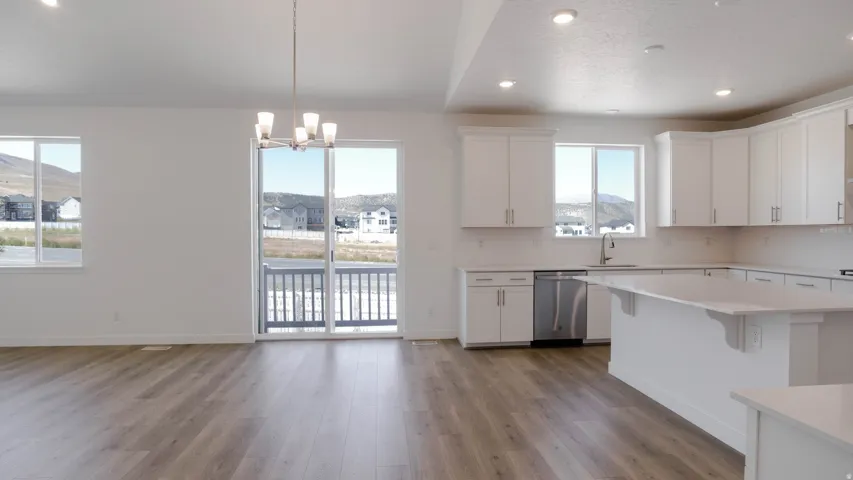Kitchen with white cabinetry, a chandelier, and stainless steel dishwasher