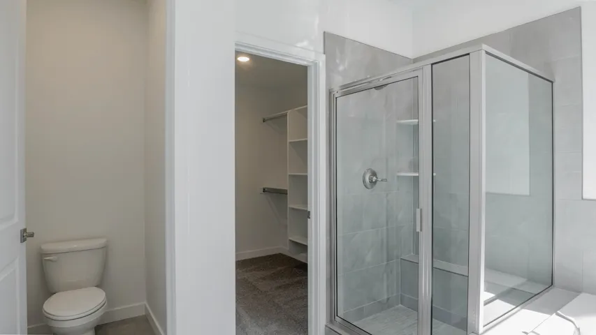 Bathroom with a shower stall and a walk in closet