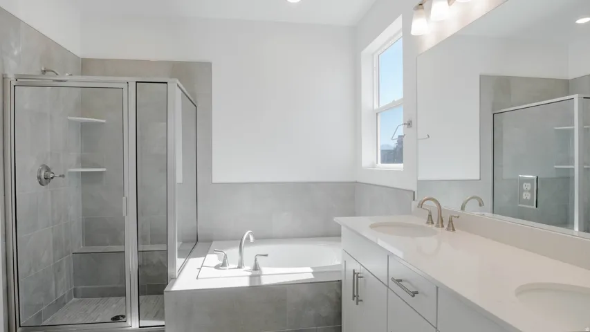Full bathroom featuring double vanity, a garden tub, and a stall shower