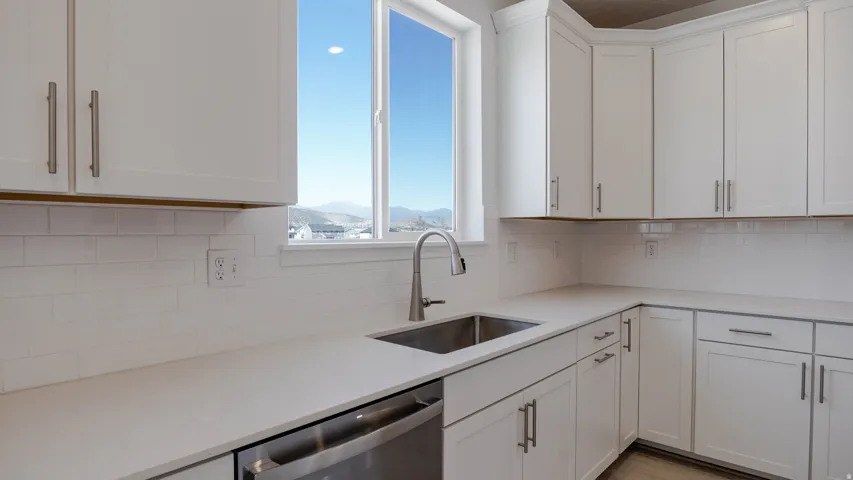 Kitchen featuring white cabinets, dishwasher, tasteful backsplash, a mountain view, and light stone counters