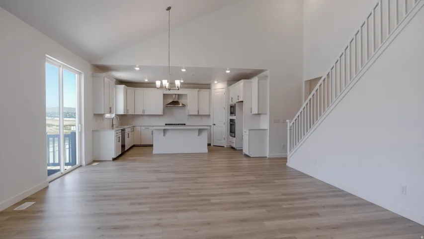 Kitchen with light countertops, a kitchen island, a kitchen breakfast bar, white cabinetry, and vaulted ceiling