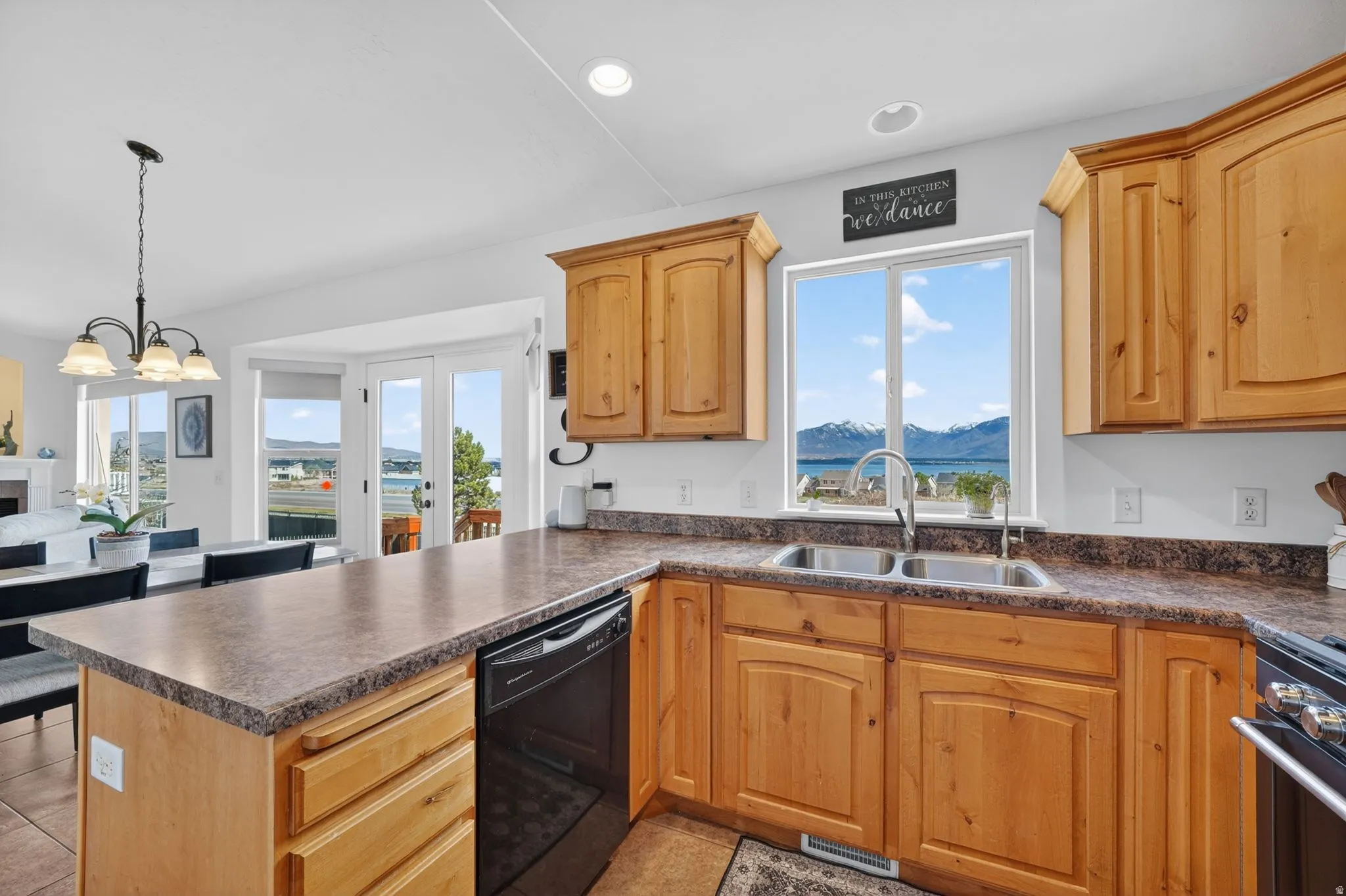 Kitchen with a peninsula, dark countertops, dishwasher, stainless steel range oven, and a chandelier