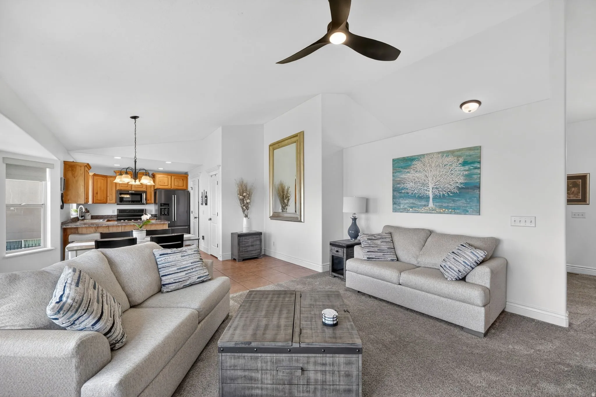 Living area with hanging lights, lofted ceiling, a ceiling fan, light carpet, and light tile patterned flooring
