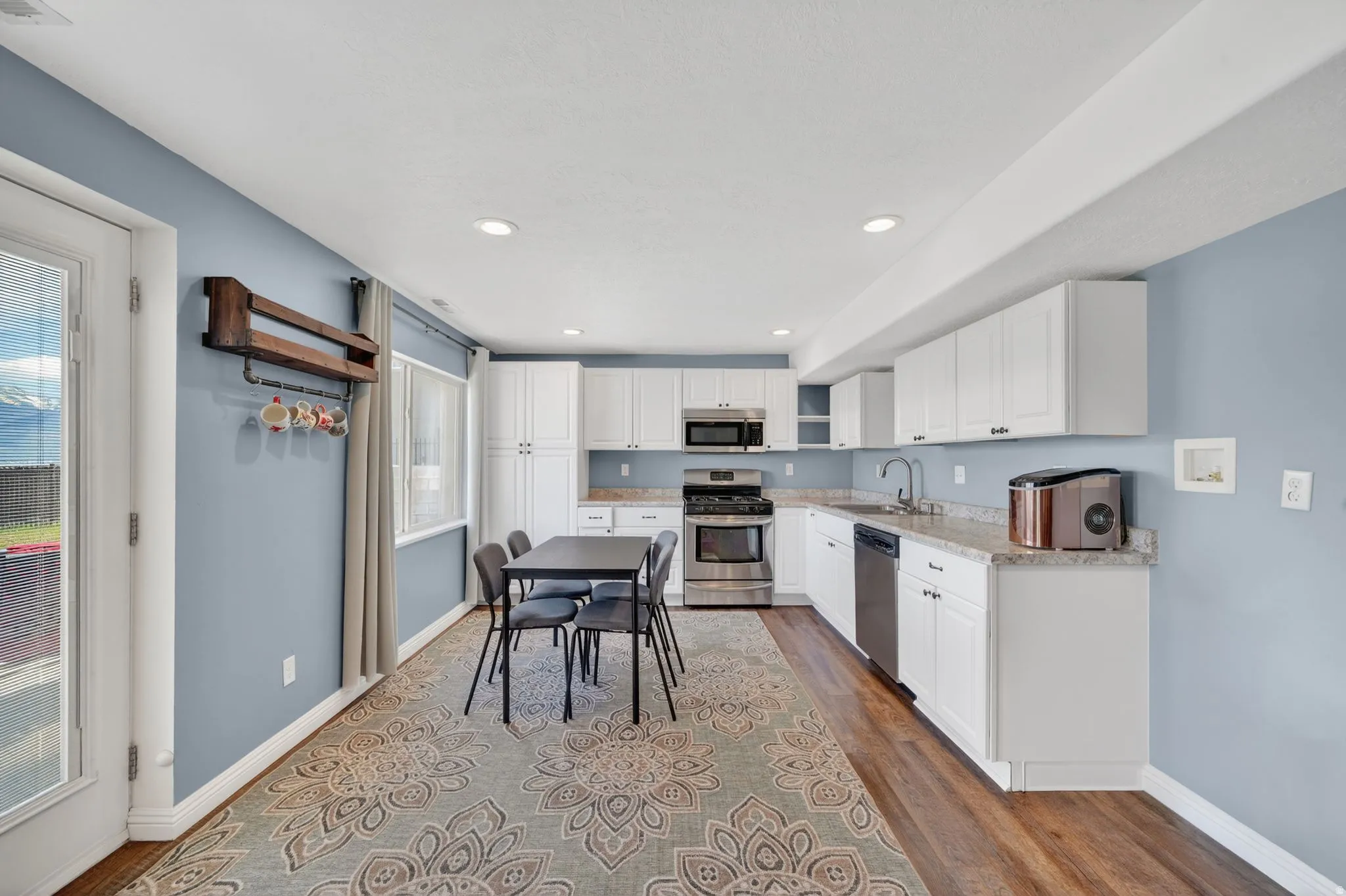 Kitchen featuring stainless steel appliances, white cabinets, light wood finished floors, light stone counters, and recessed lighting
