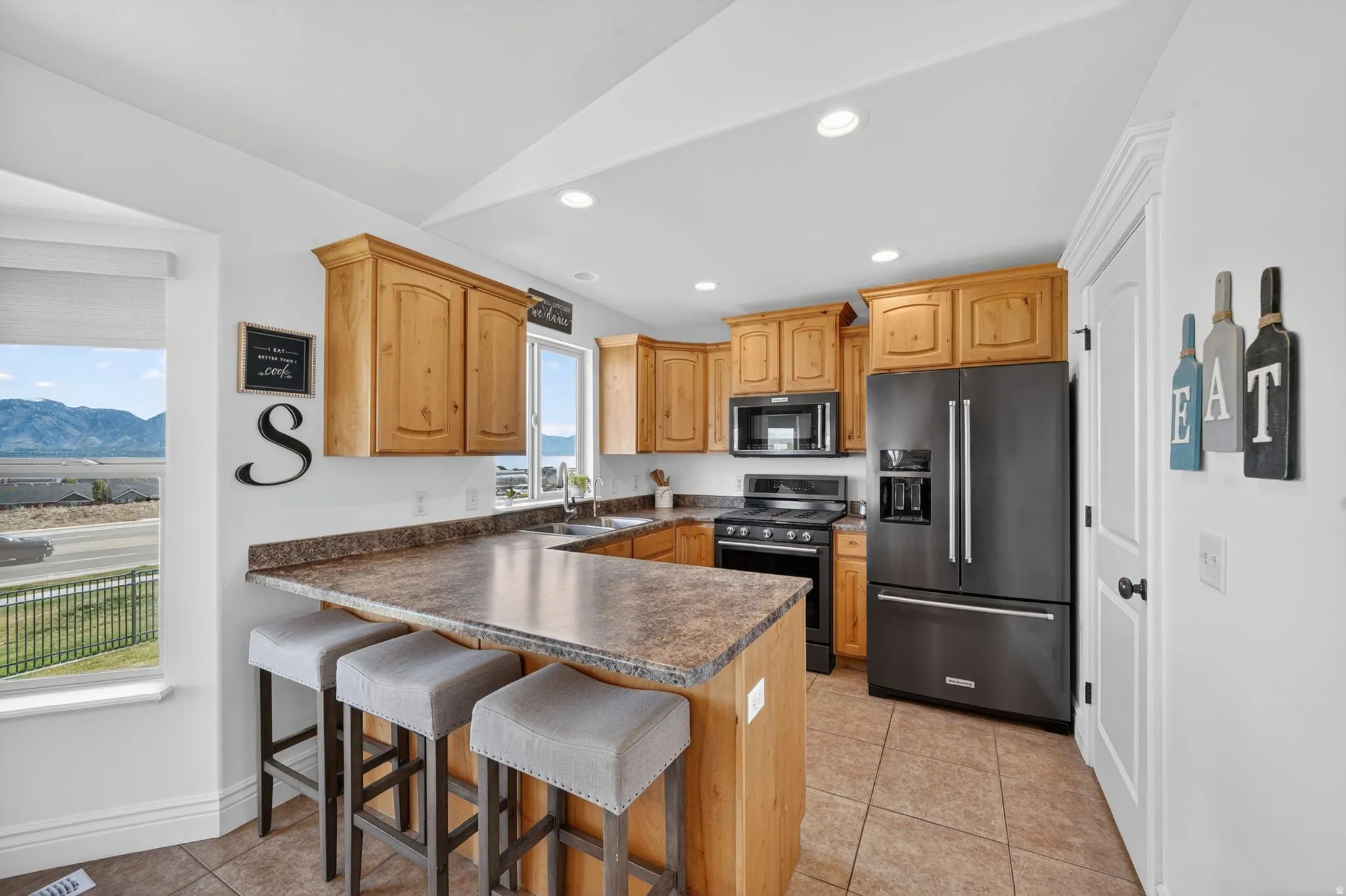 Kitchen with a kitchen breakfast bar, high quality fridge, a peninsula, dark countertops, and gas stove