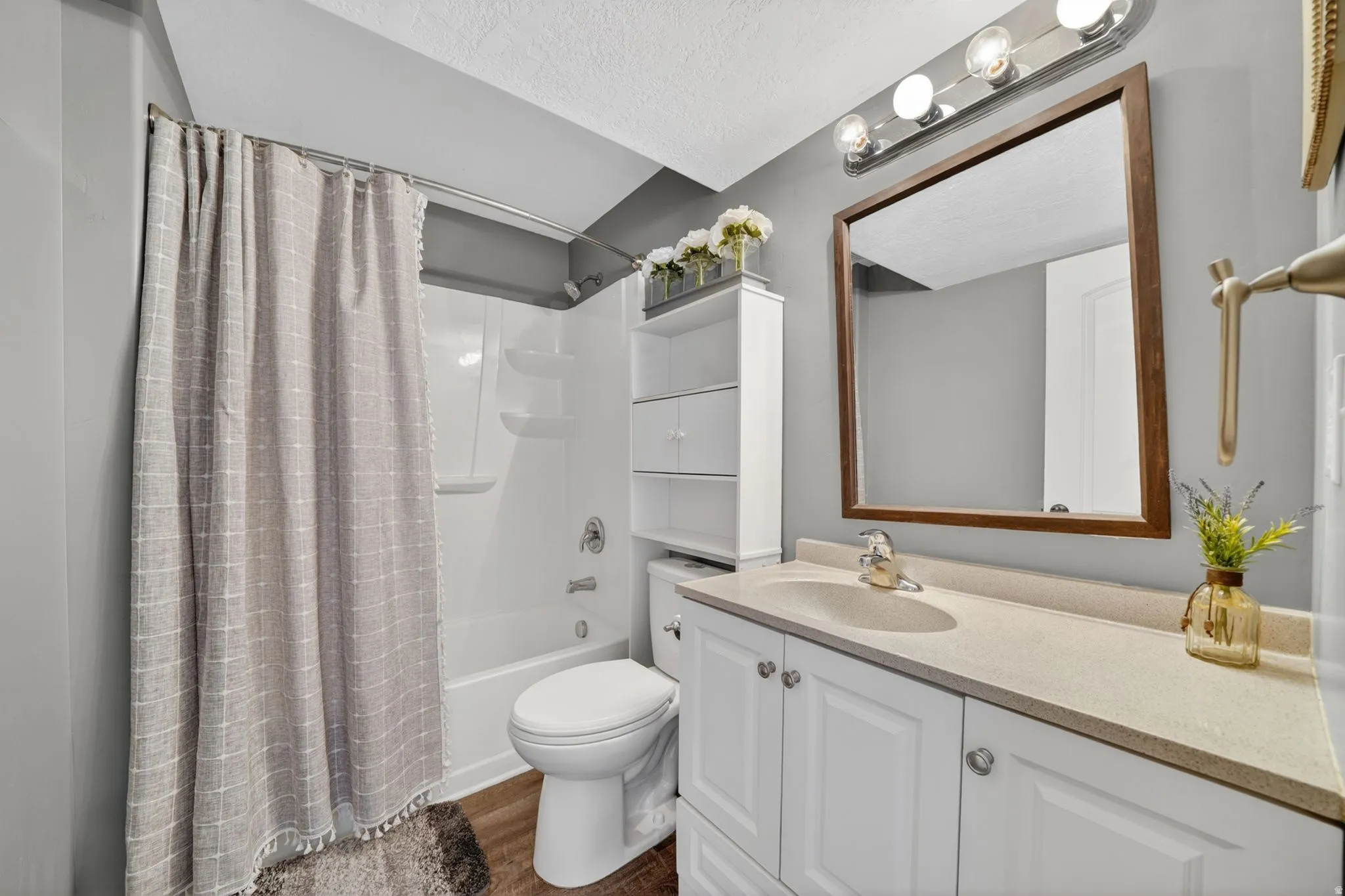 Full bathroom featuring vanity, shower / bath combo with shower curtain, a textured ceiling, and dark wood-style flooring