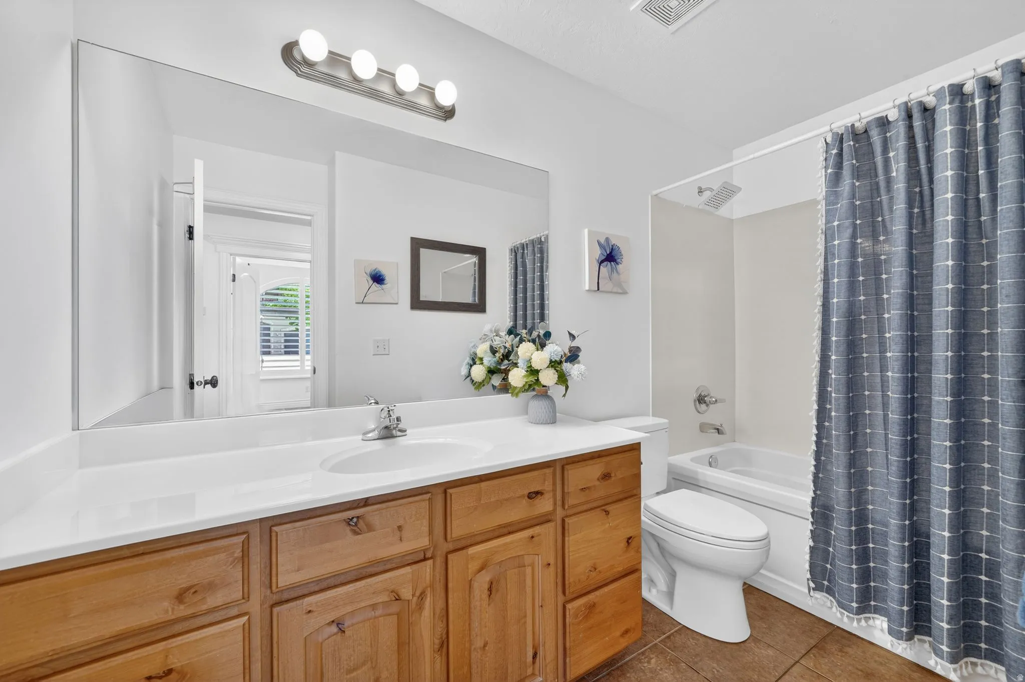 Bathroom with vanity, shower / bath combination with curtain, and dark tile patterned flooring