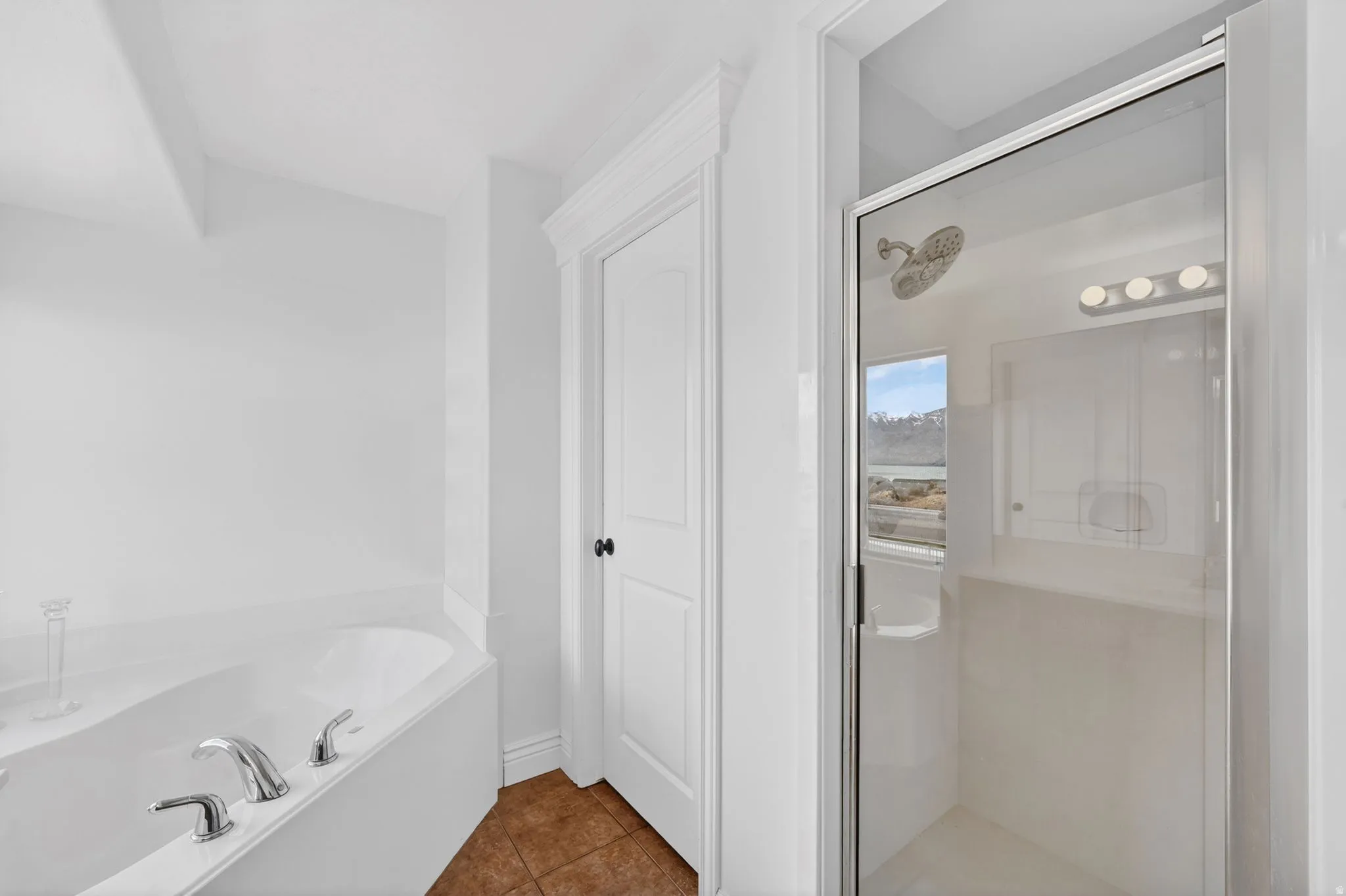 Full bath featuring a shower stall, dark tile patterned floors, and a bath