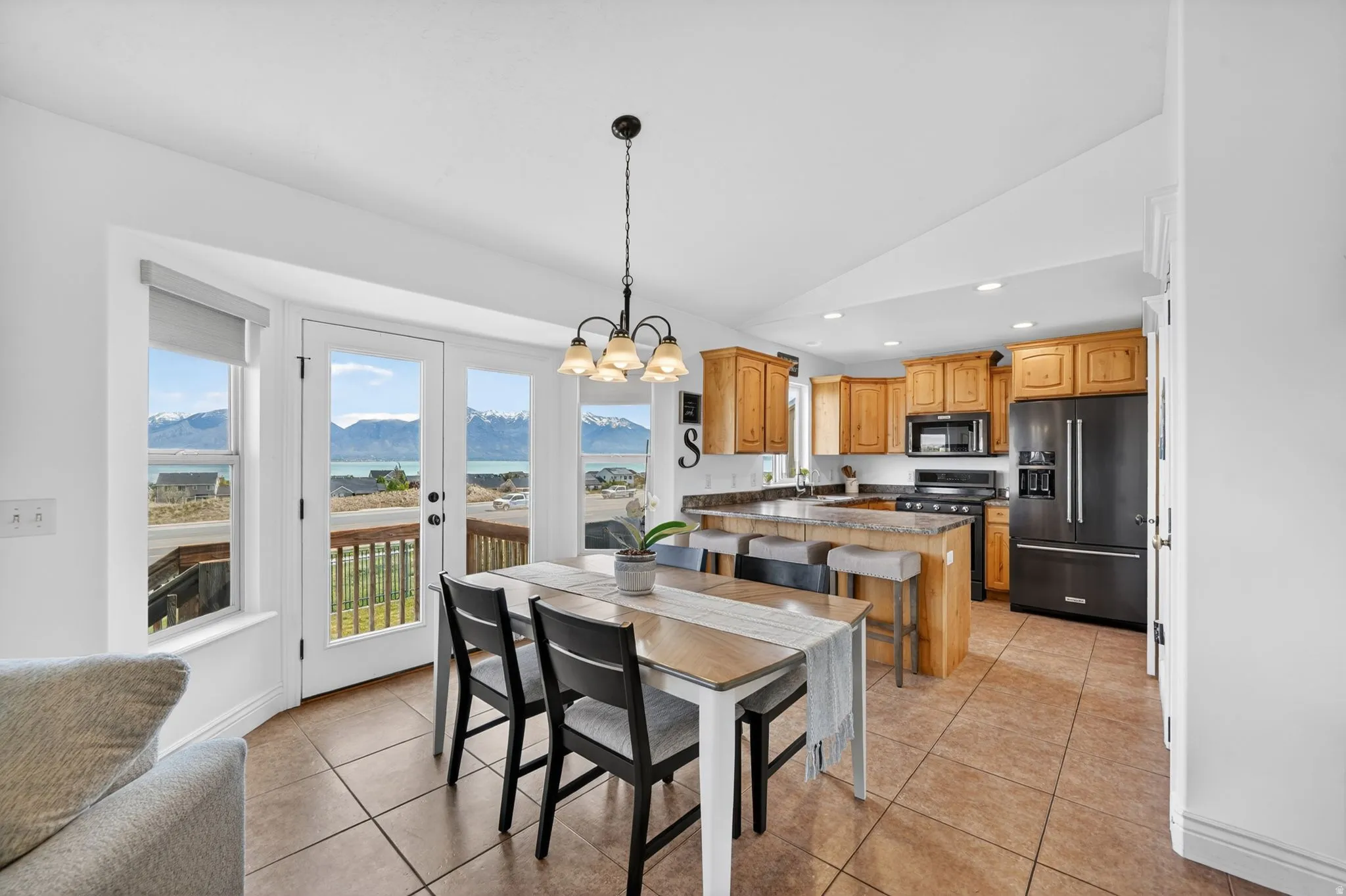 Dining area featuring lofted ceiling, suspended lighting, a mountain view, light tile patterned floors, and french doors
