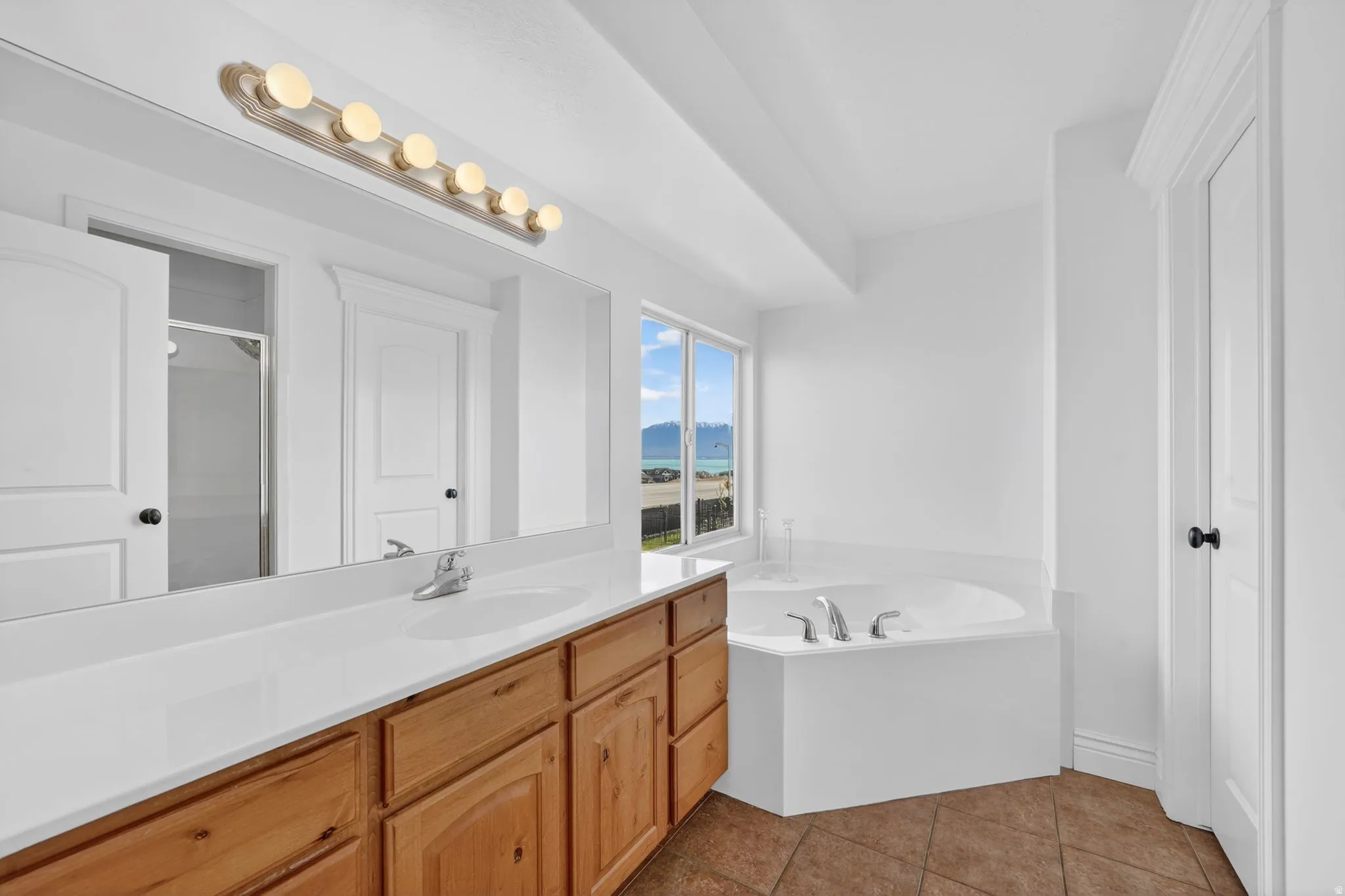 Full bath featuring vanity, a bath, dark tile patterned flooring, and a shower stall