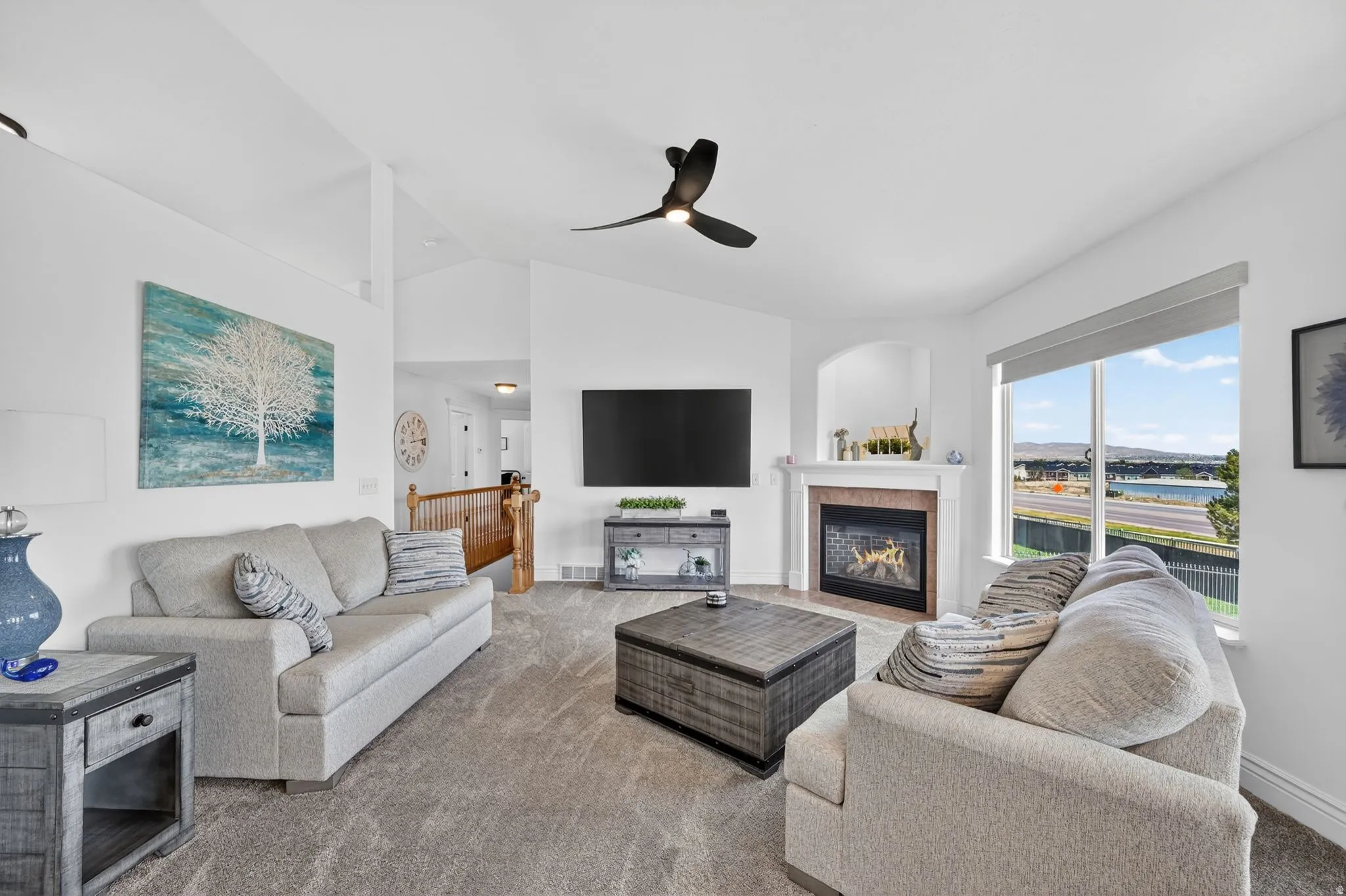 Living area with vaulted ceiling, a fireplace, carpet, and ceiling fan