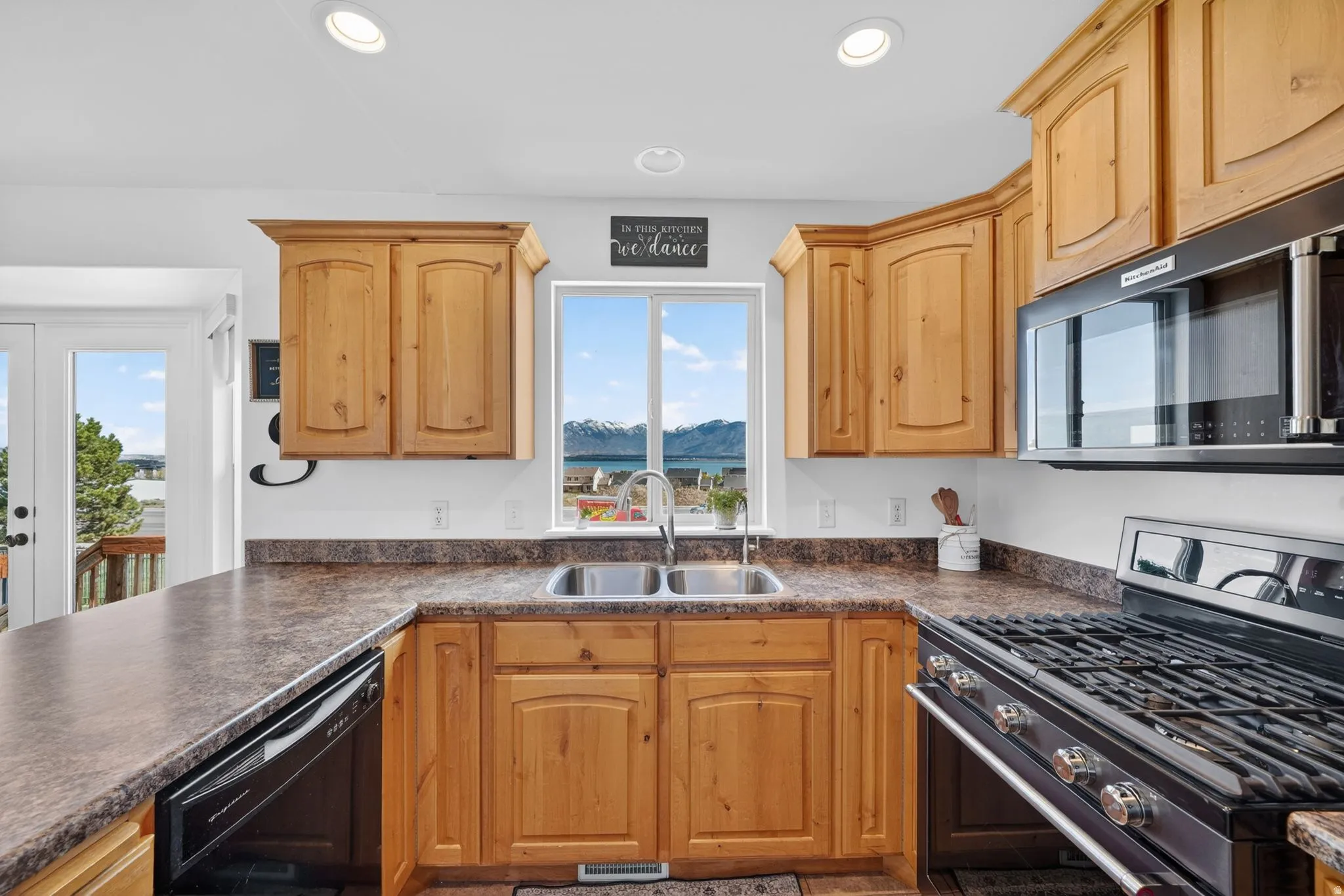 Kitchen with stainless steel range with gas cooktop, dark countertops, dishwasher, and recessed lighting