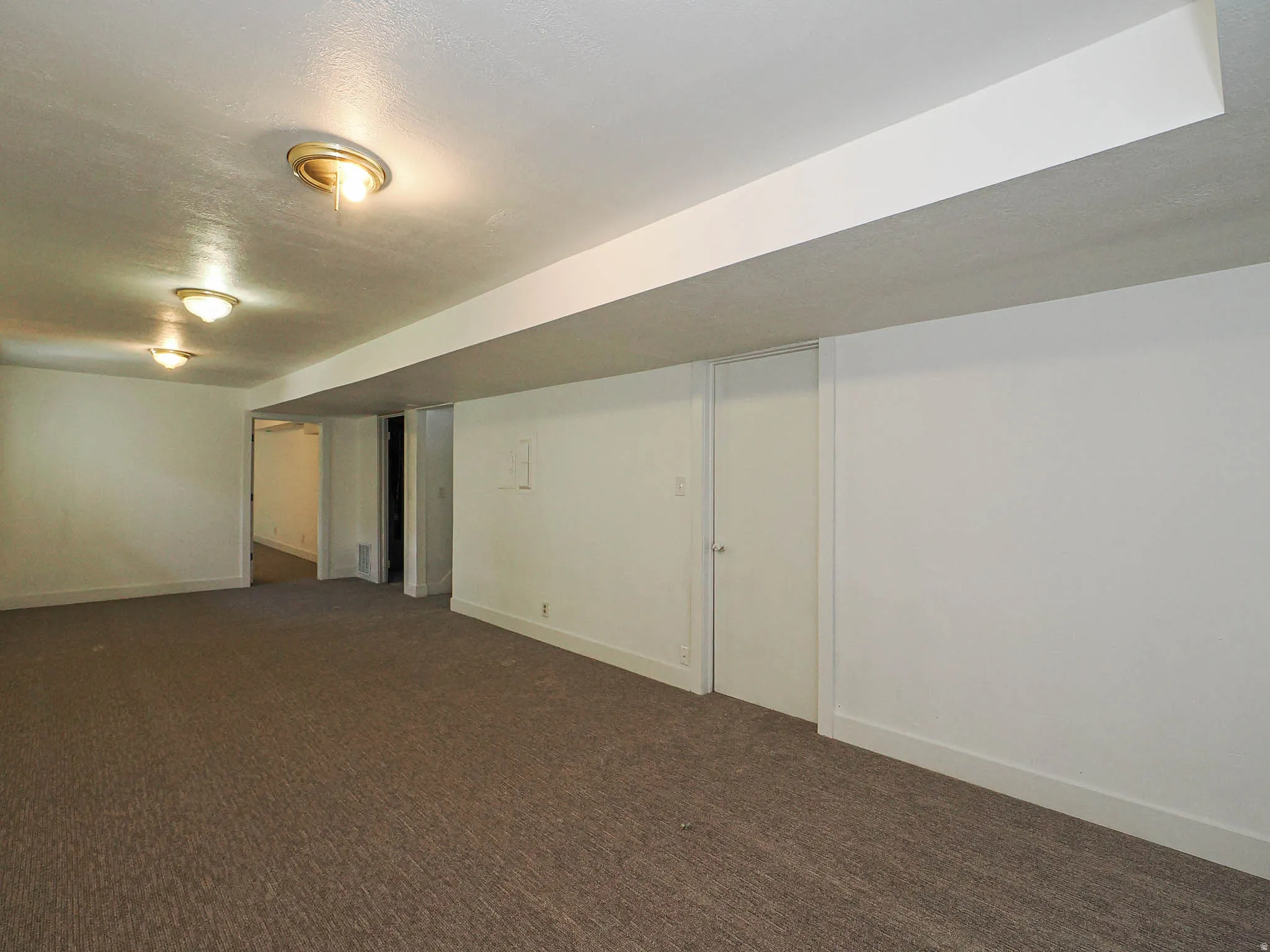Finished basement featuring dark colored carpet and a textured ceiling