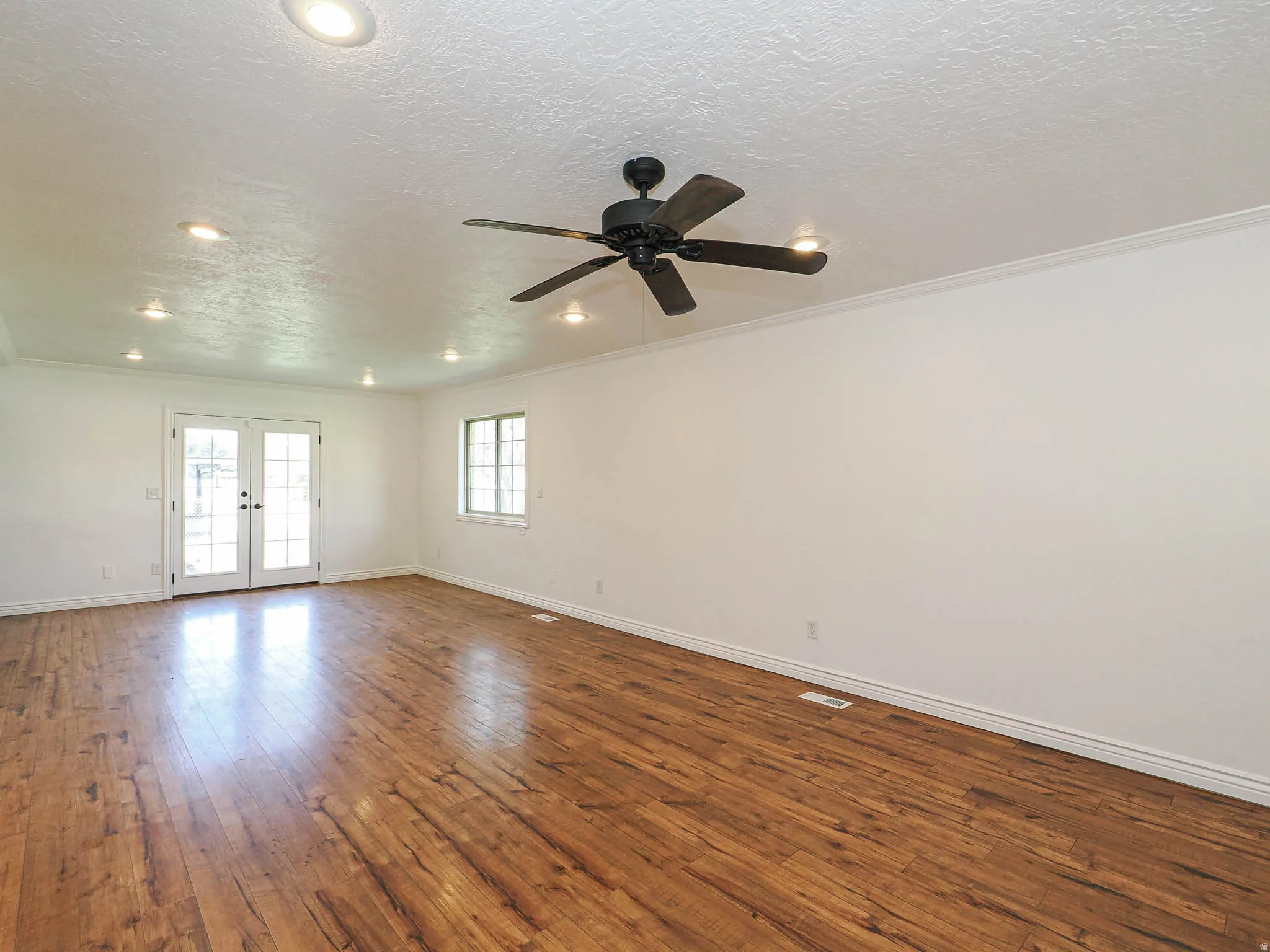 Spare room with french doors, dark wood finished floors, a textured ceiling, a ceiling fan, and crown molding