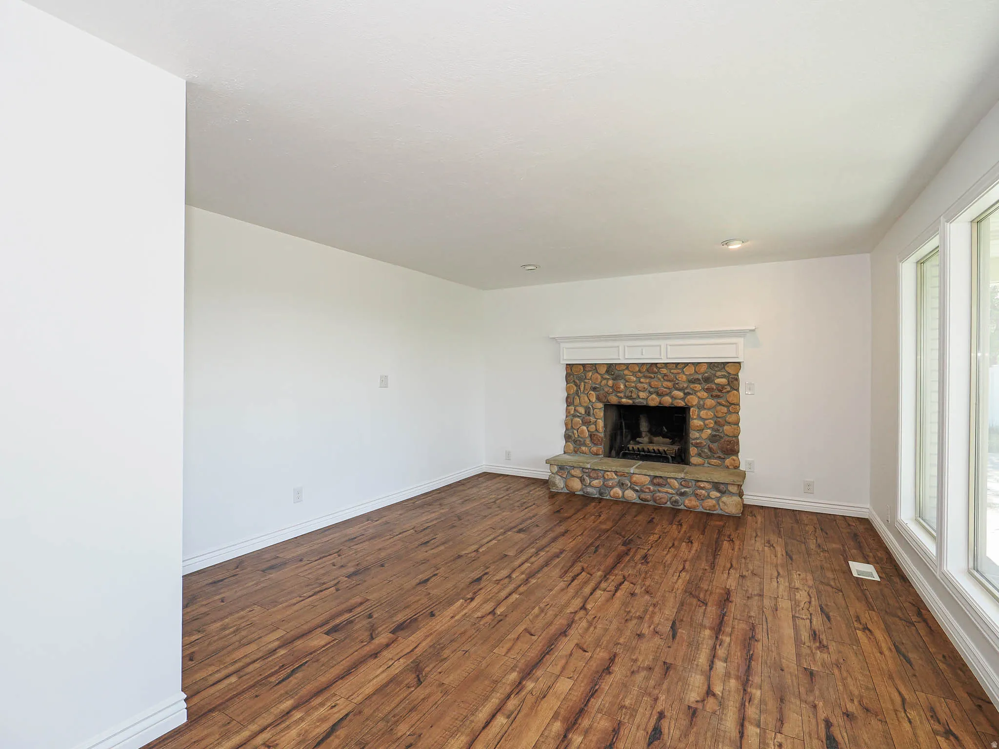 Unfurnished living room featuring dark wood finished floors and a fireplace