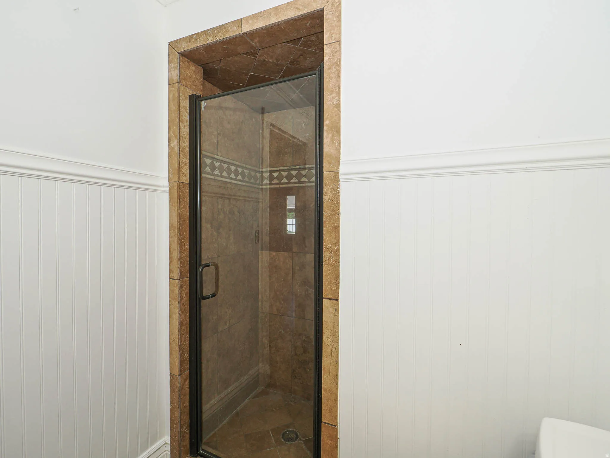Bathroom featuring a wainscoted wall and a shower stall