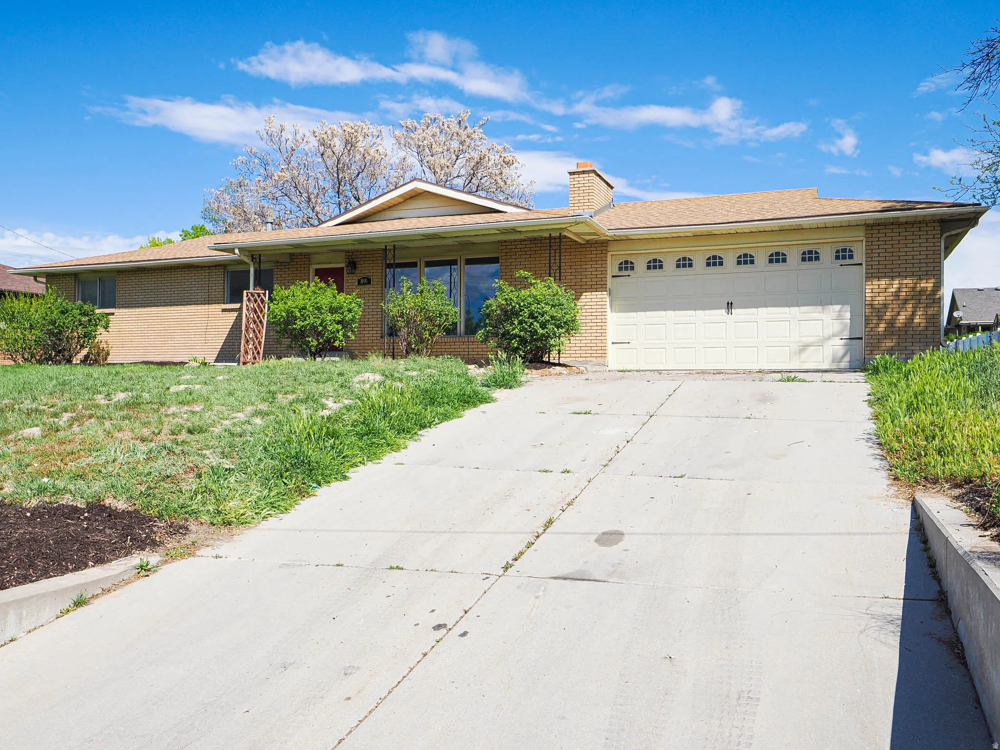 Ranch-style house featuring driveway, a garage, a chimney, and brick siding