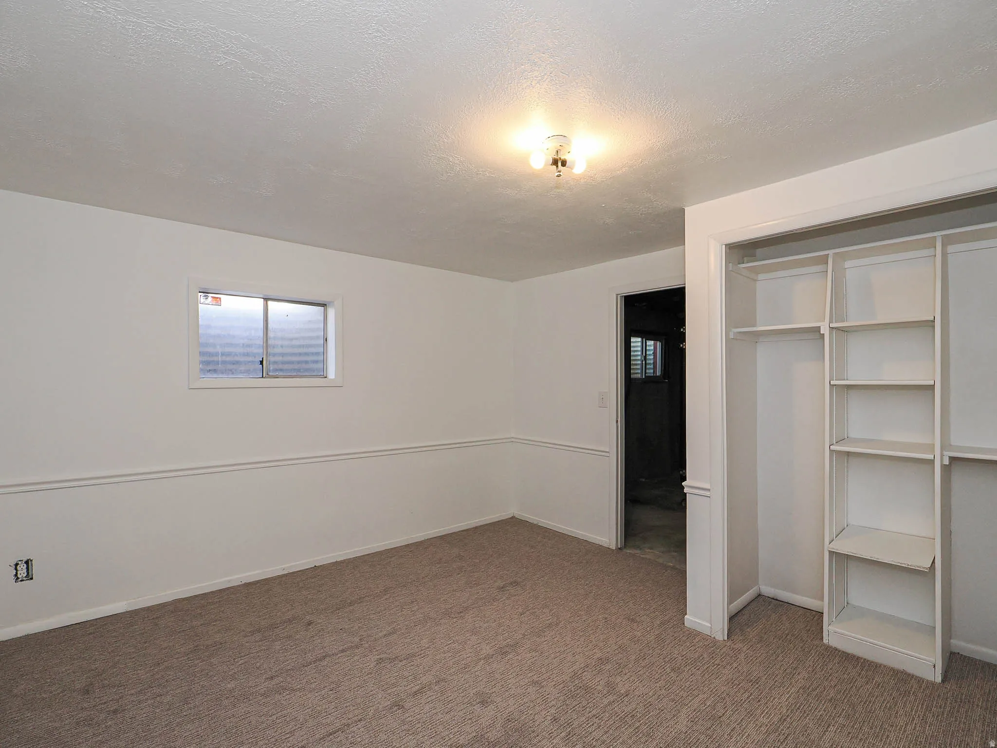 Unfurnished bedroom with a closet, dark colored carpet, and a textured ceiling