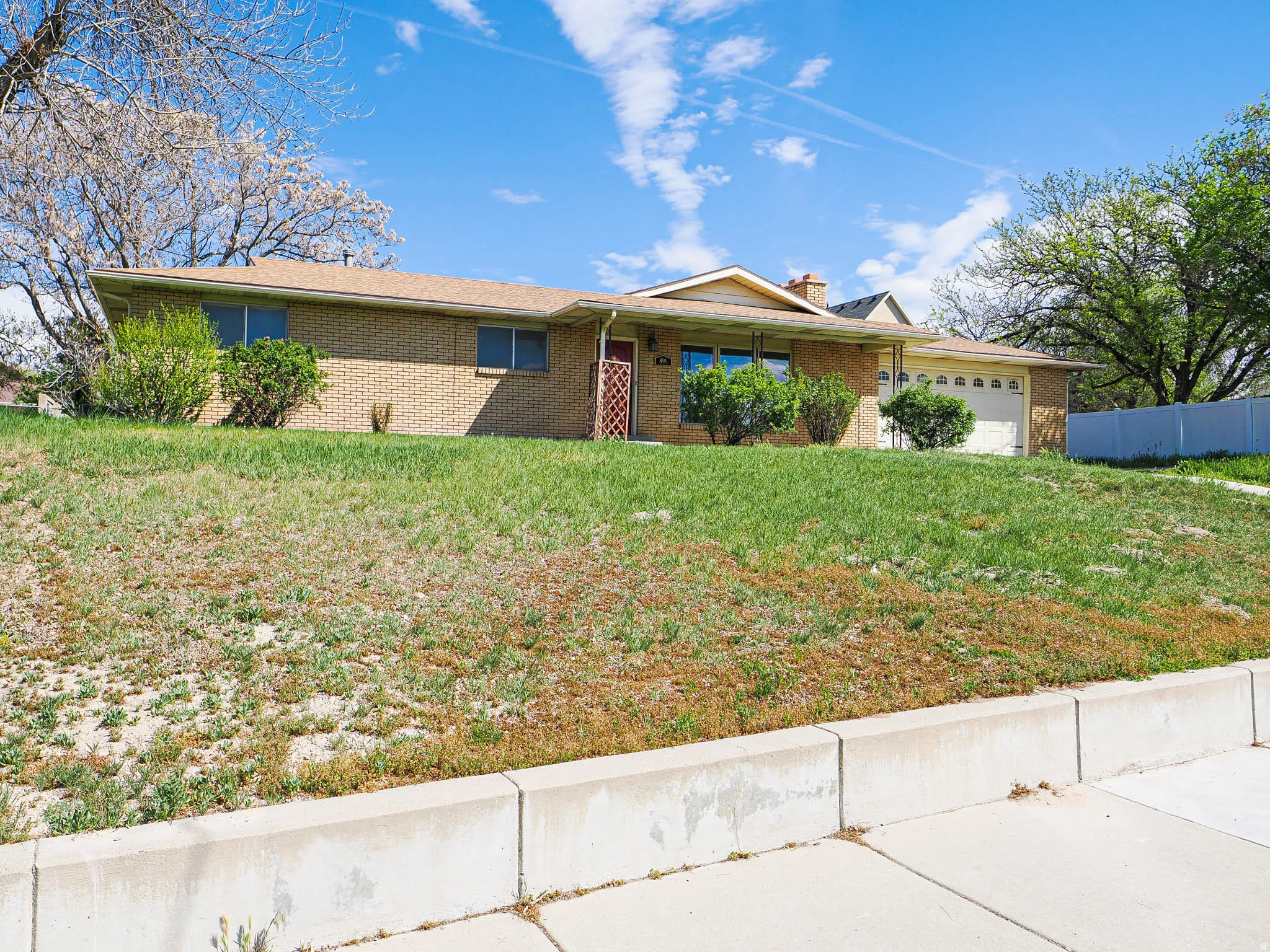 Ranch-style house featuring an attached garage, brick siding, and a chimney