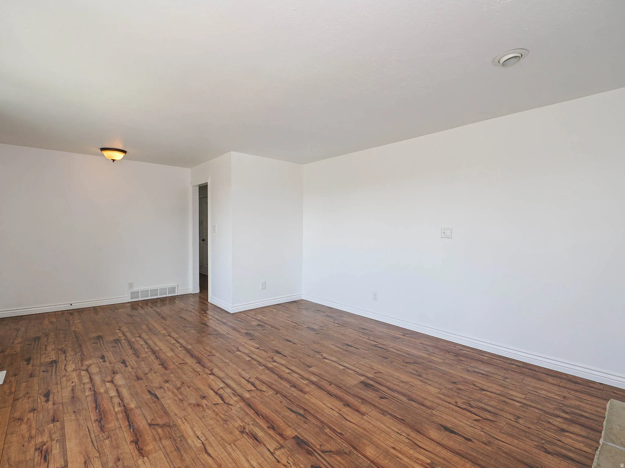 Empty room featuring dark wood-type flooring and baseboards