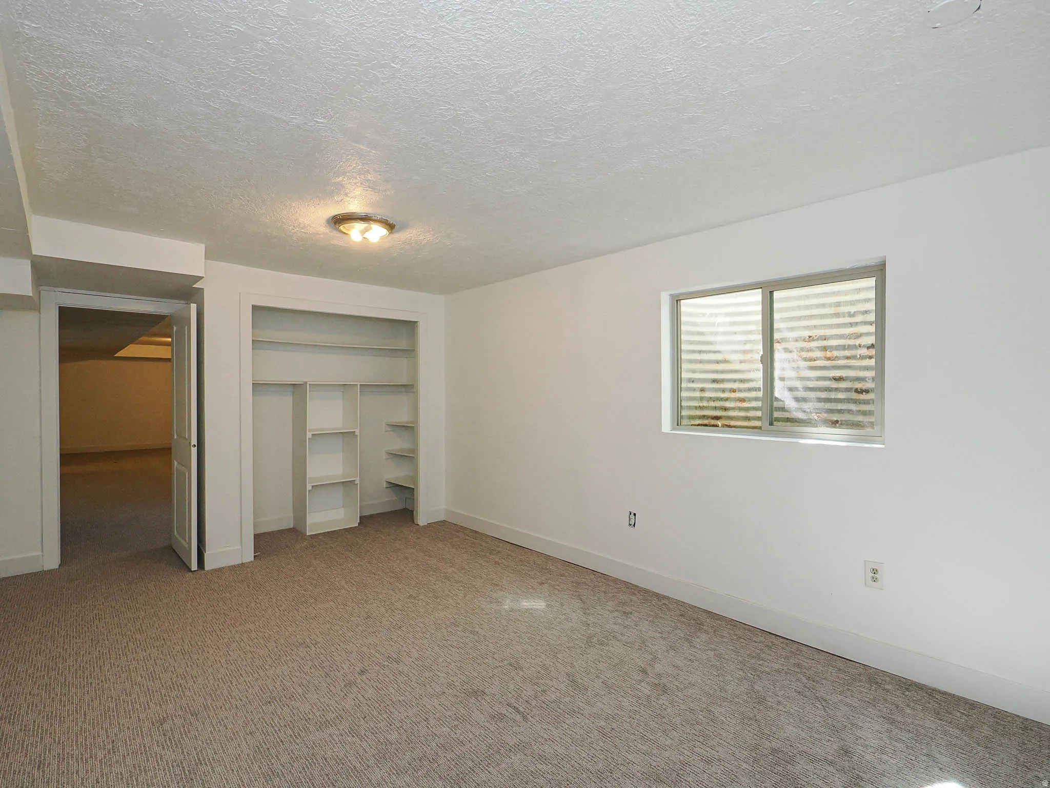Unfurnished bedroom featuring a textured ceiling, carpet floors, and a closet
